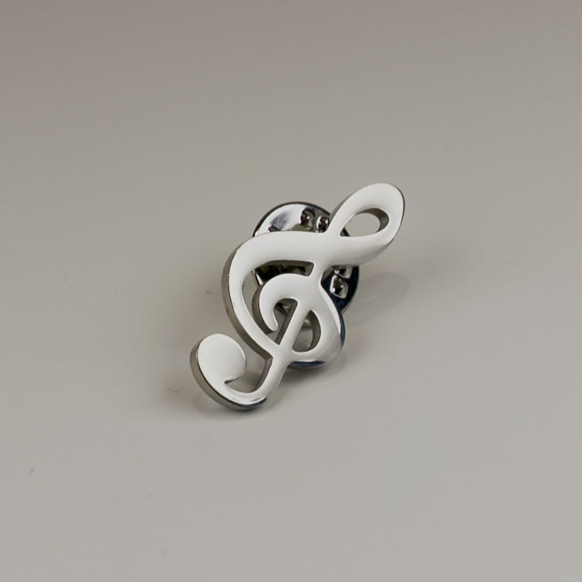 White treble clef brooch on a gray background