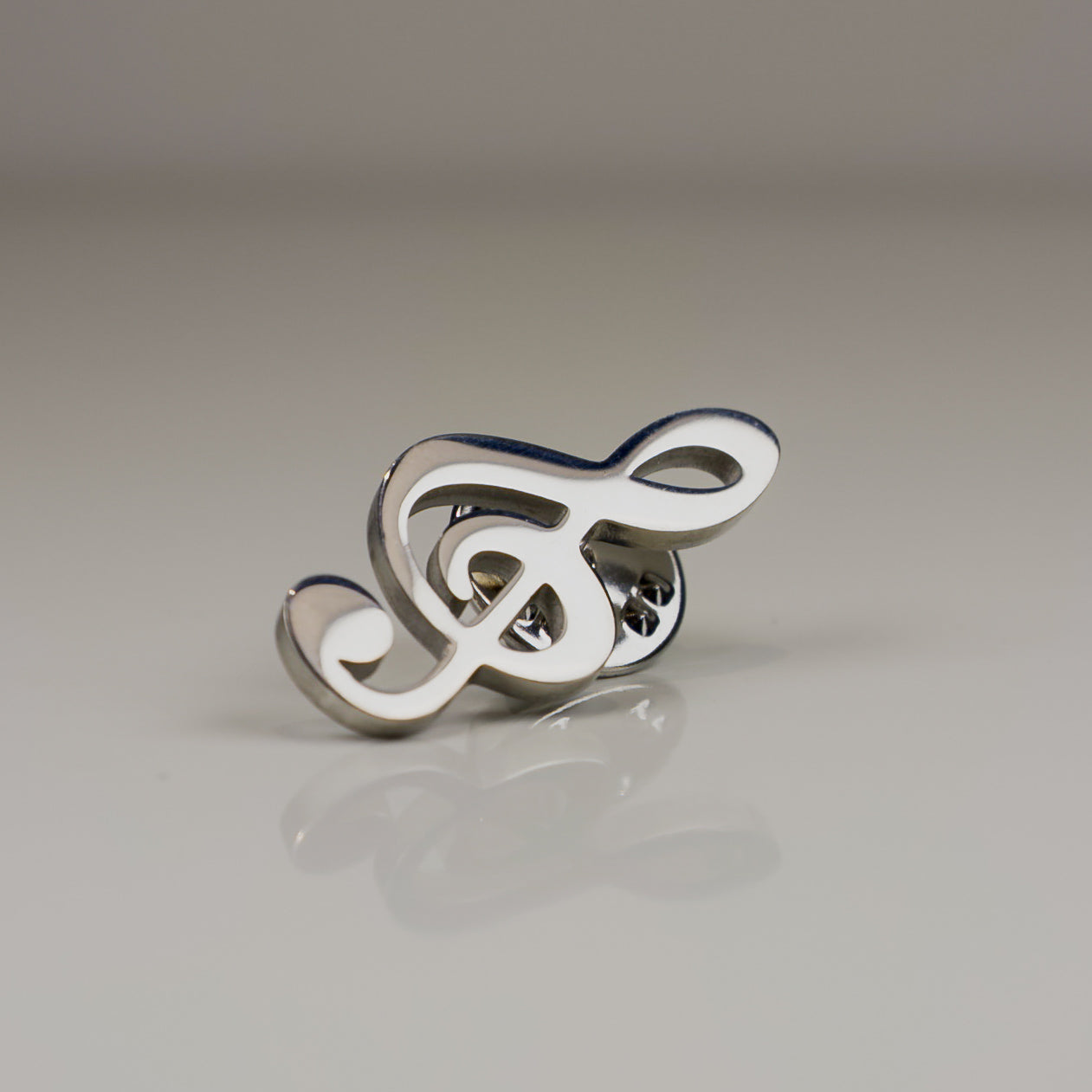 Silver and white decorative item on a reflective surface with a neutral background