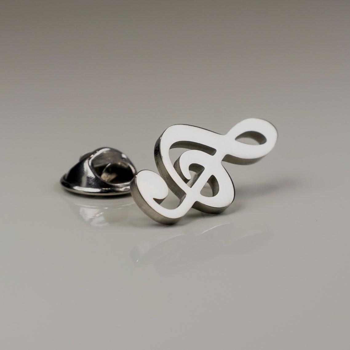 Metallic music symbol pin on a gray background