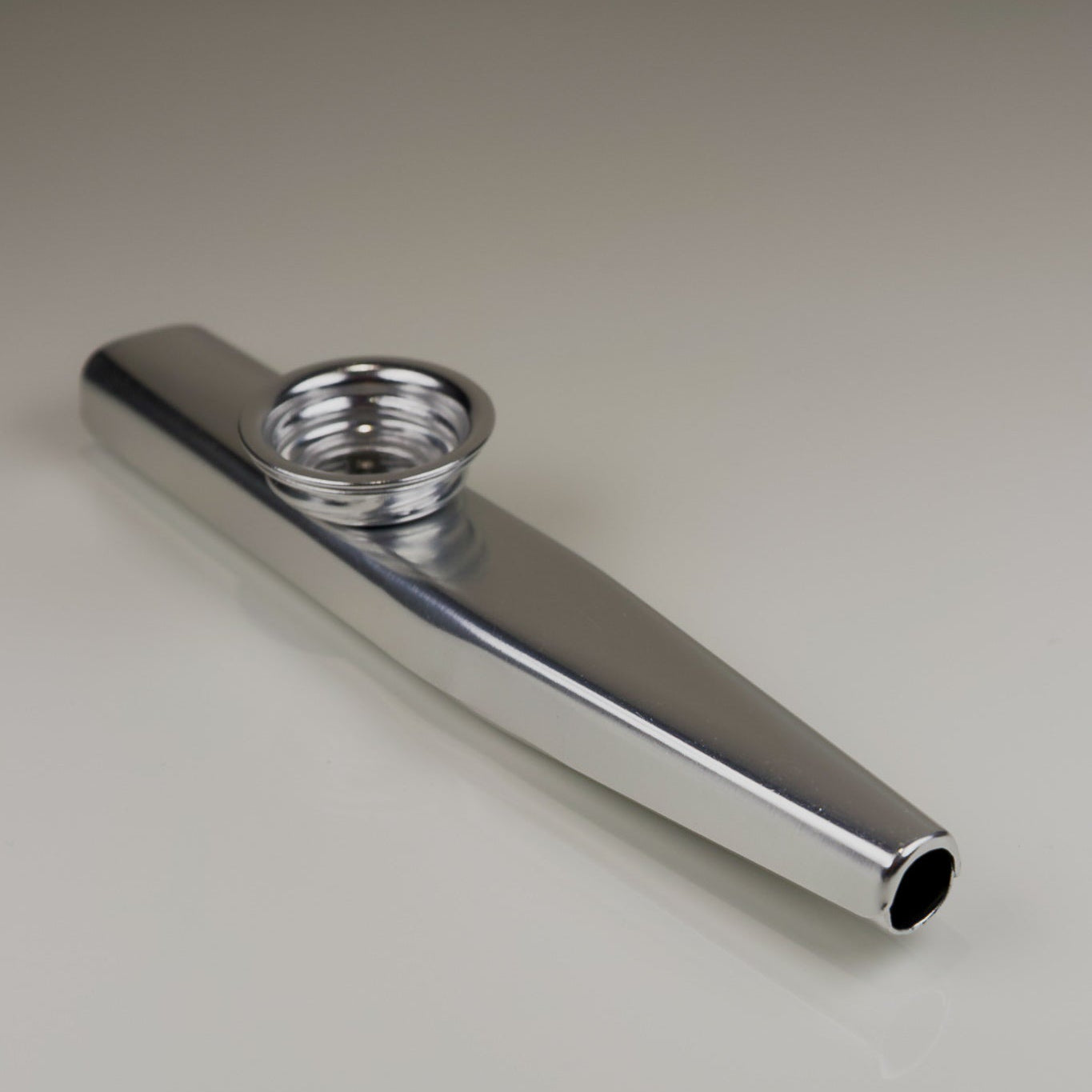 Chrome metal kazoo on a light gray background