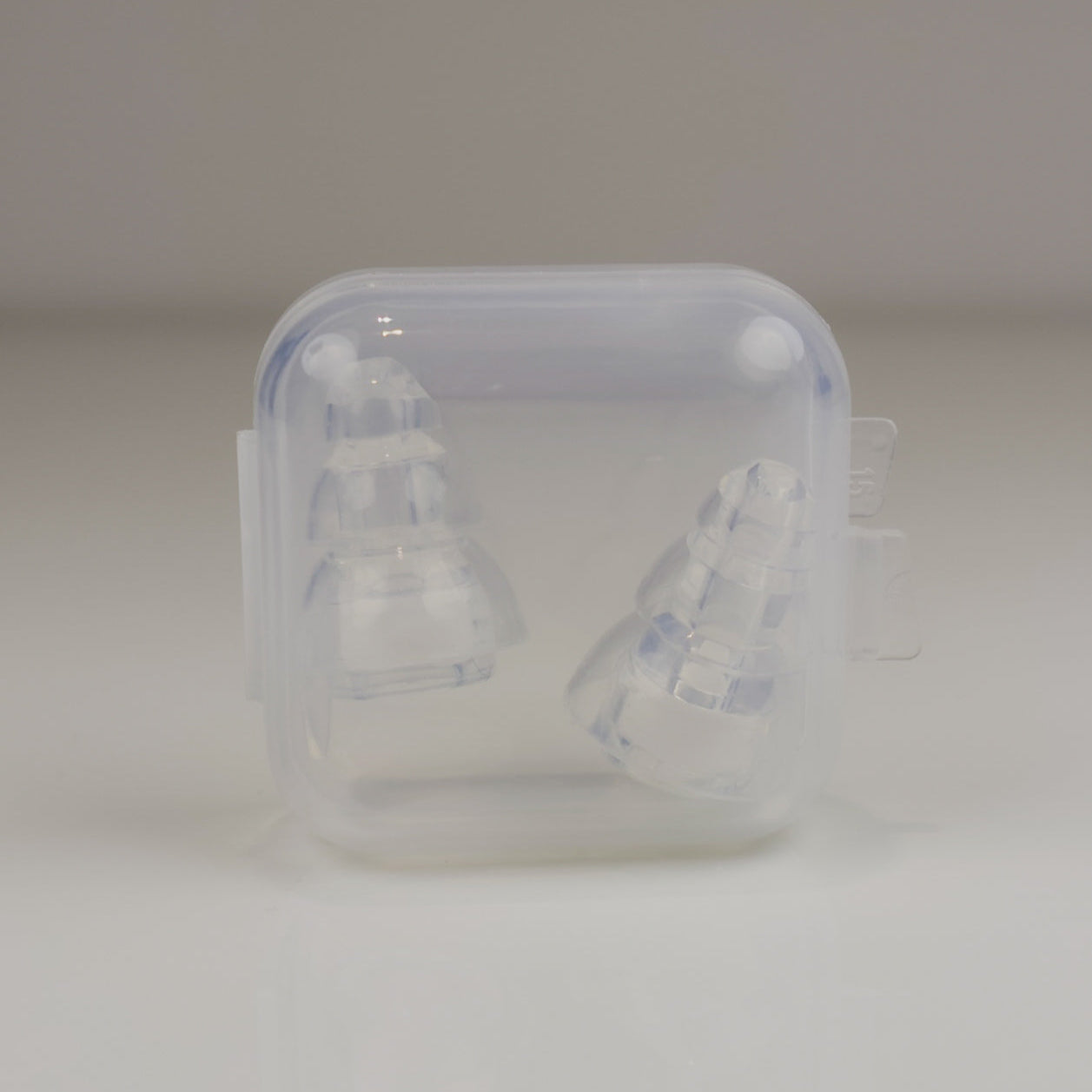 Clear plastic container with two white objects inside on a light gray background