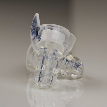 Clear plastic earbud on a reflective surface with a neutral background