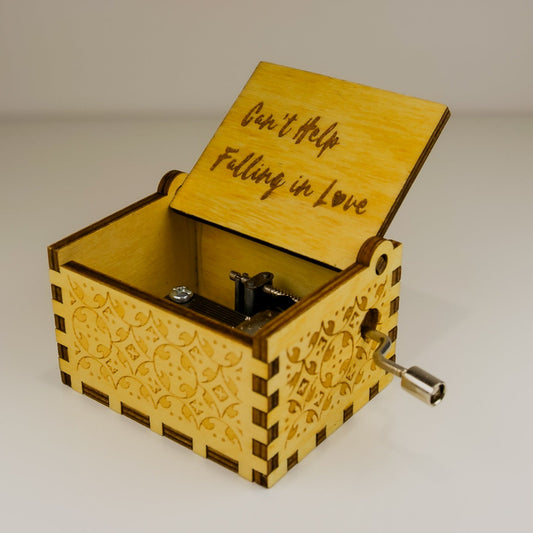 Wooden music box with 'Can't Help Falling in Love' engraving on a light background