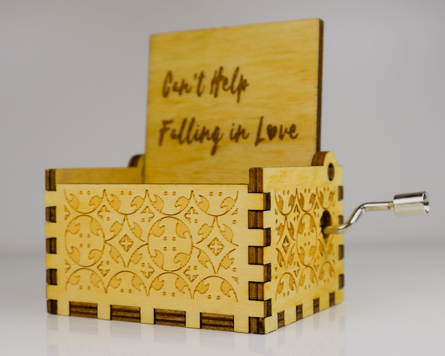 Wooden music box with engraved design and text on a gray background