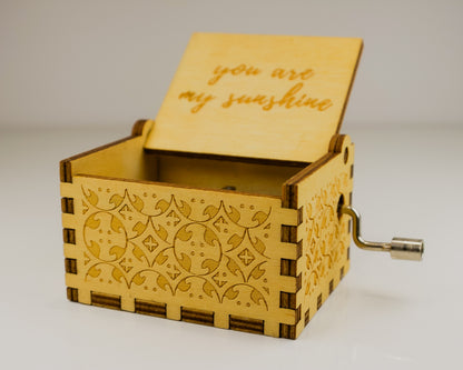 Wooden music box with 'you are my sunshine' engraving on a light background