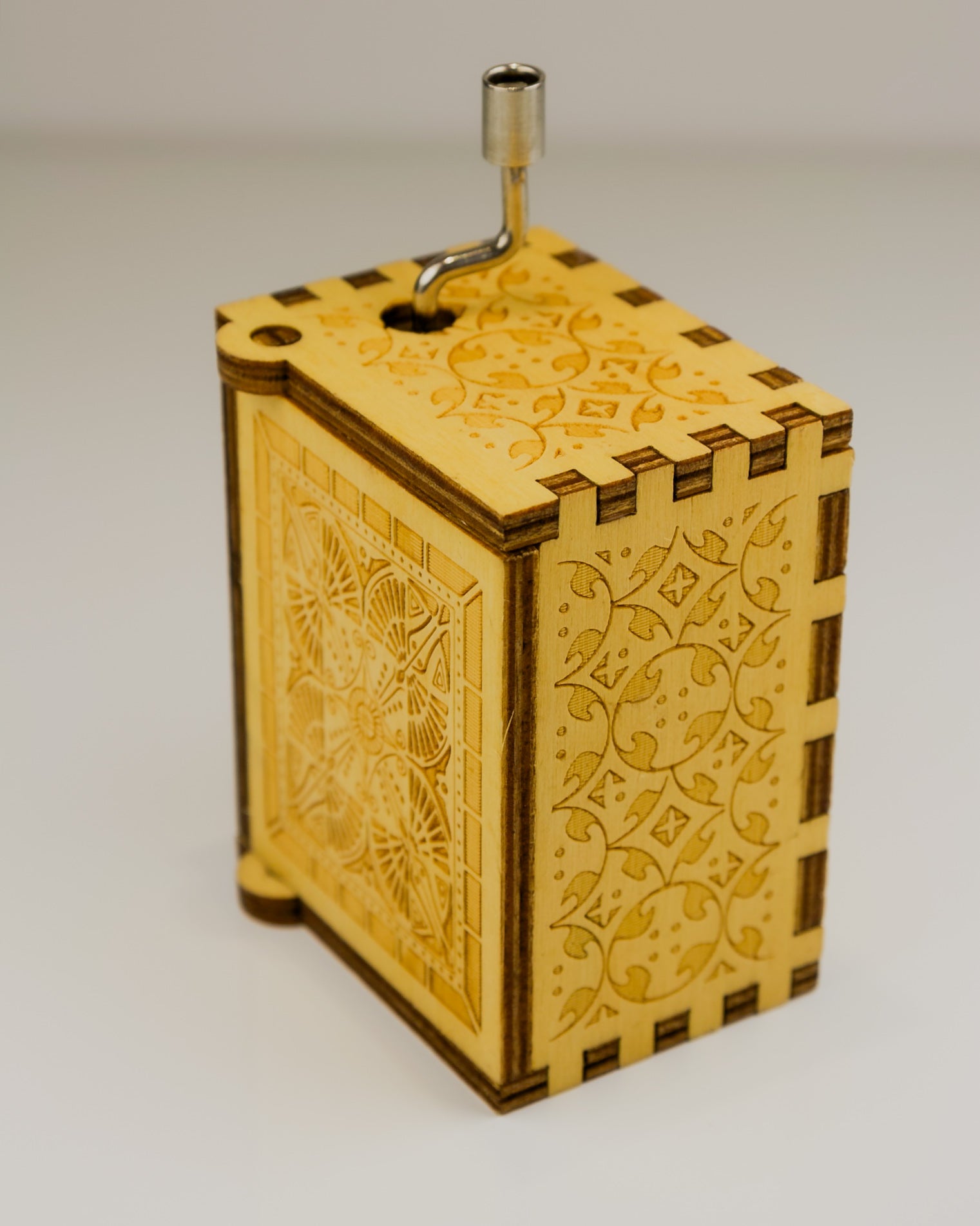 Wooden music box with intricate laser-cut designs on a plain background
