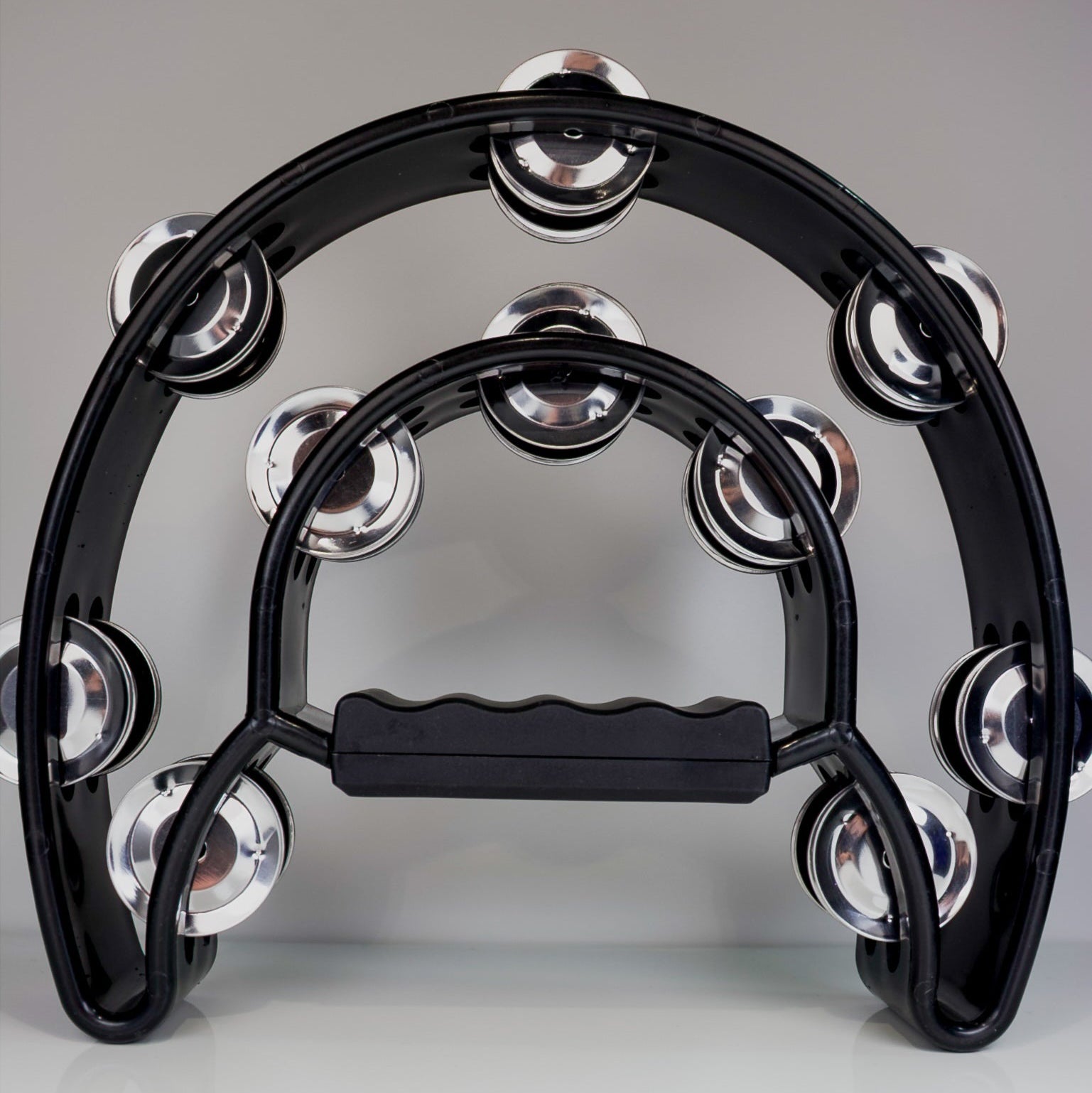 Black tambourine with silver jingles on a gray background