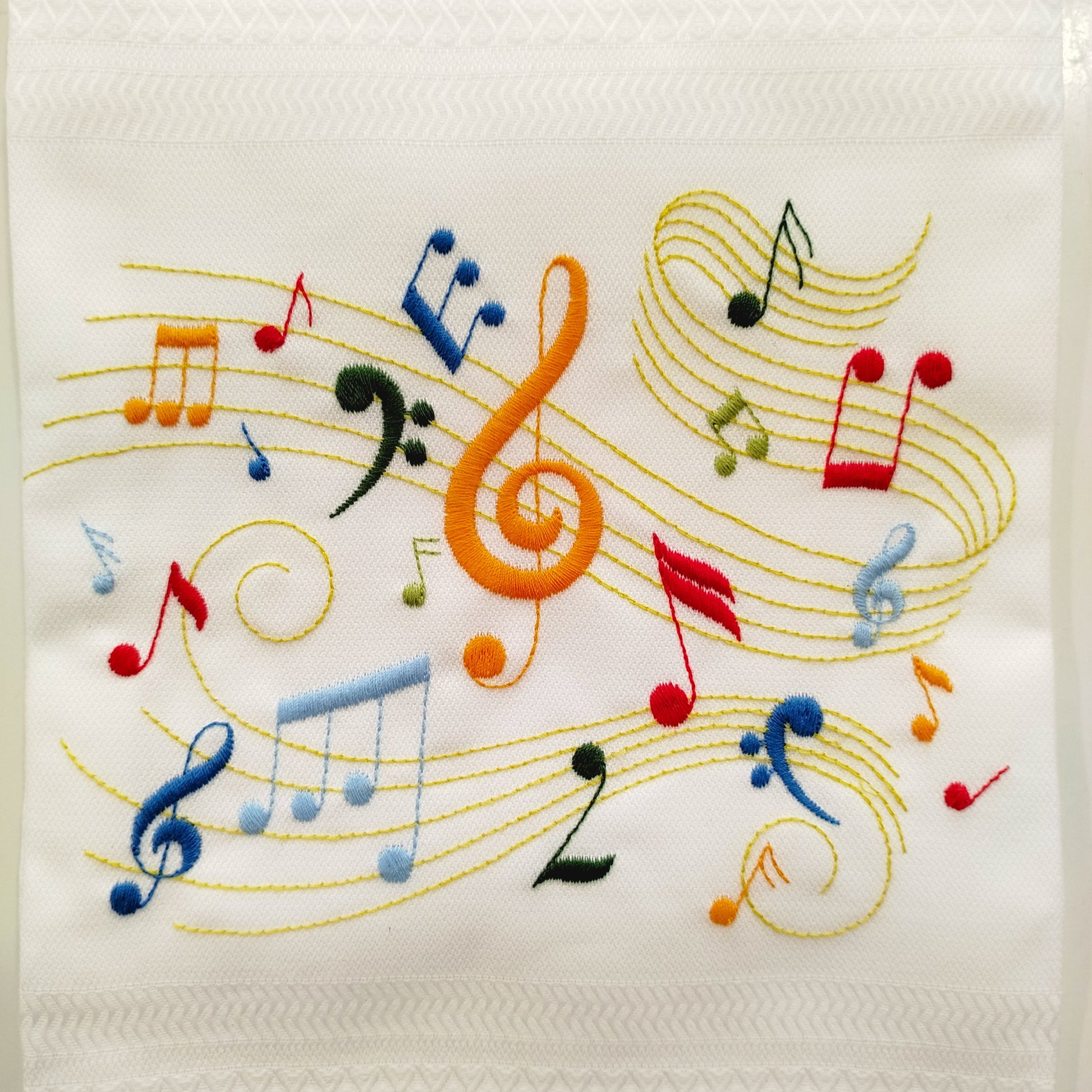 Embroidered design of musical notes on a white fabric background