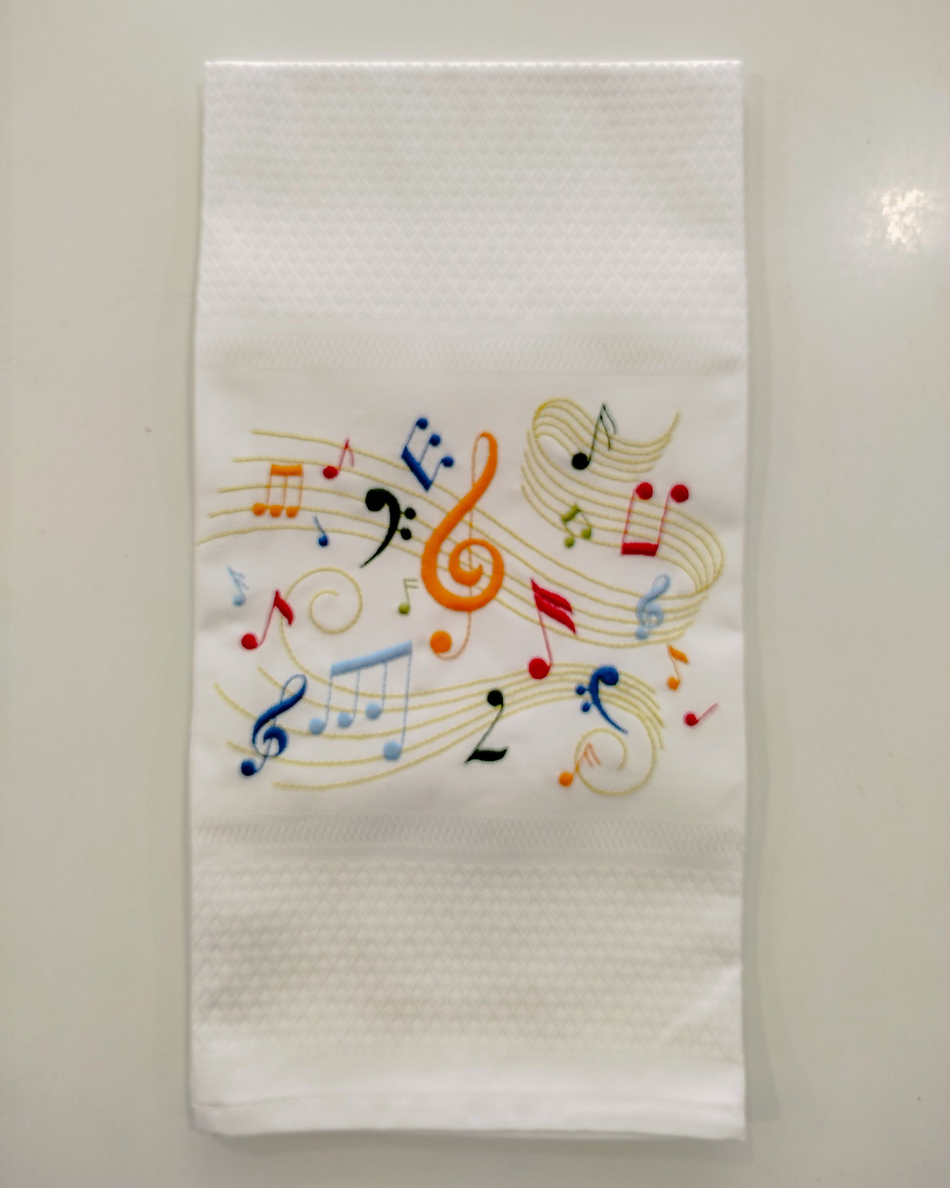 Kitchen White towel with colorful embroidered music notes on a light gray background