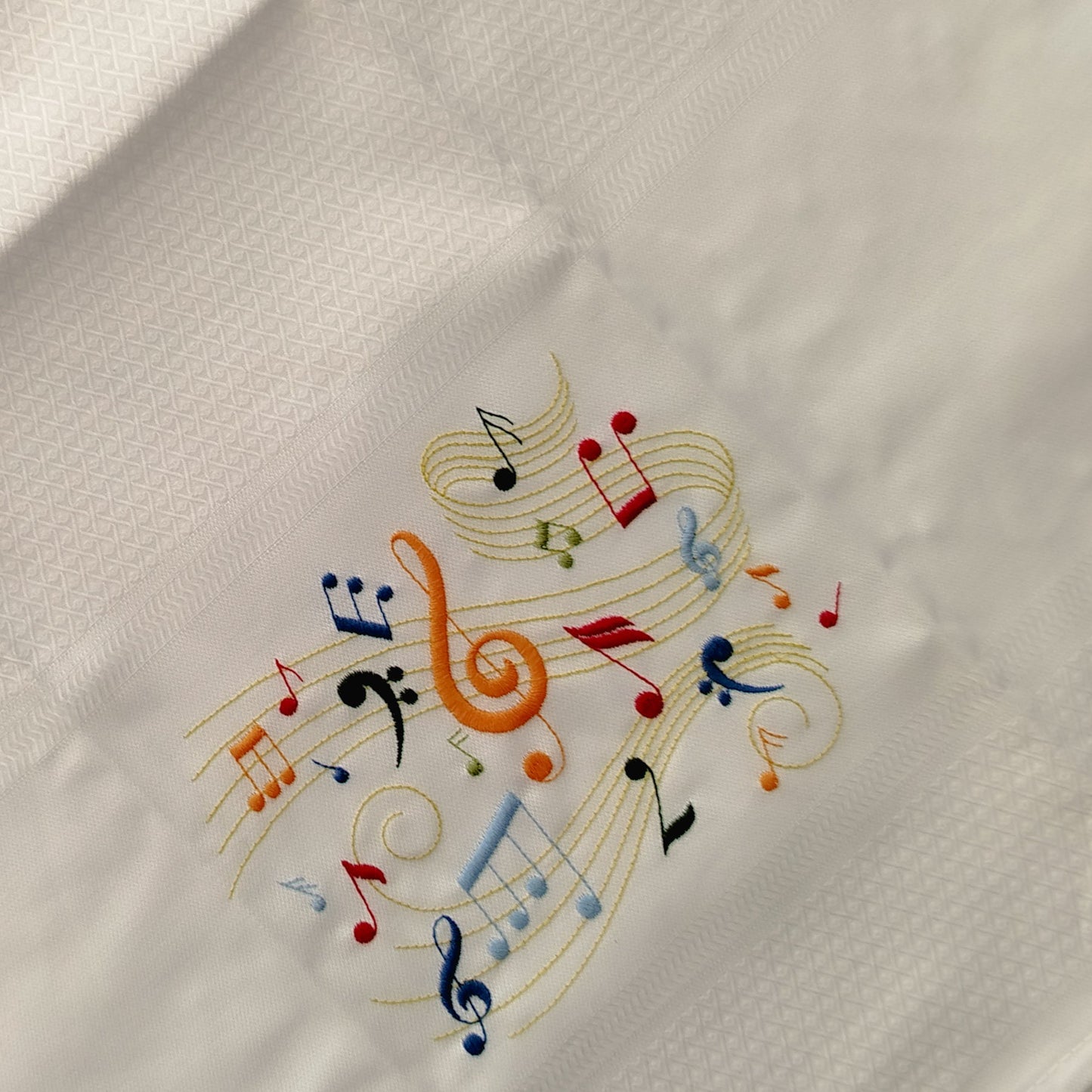 Embroidered design of colorful musical notes on a white fabric background