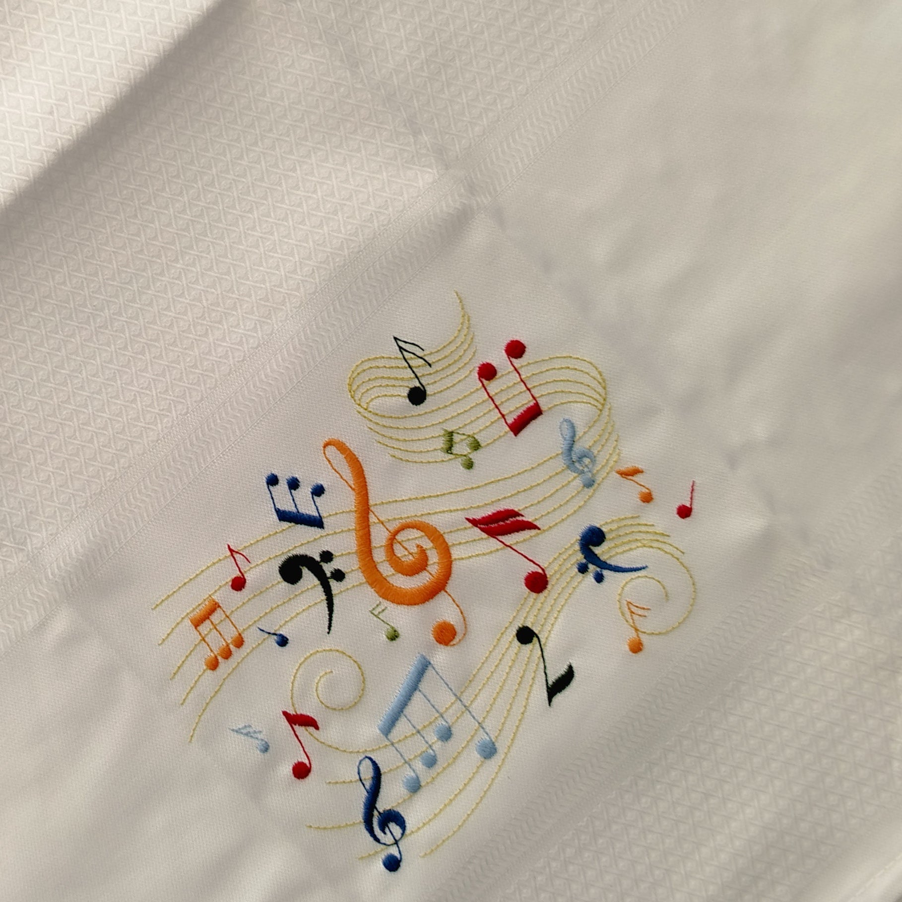 Embroidered design of colorful musical notes on a white fabric background